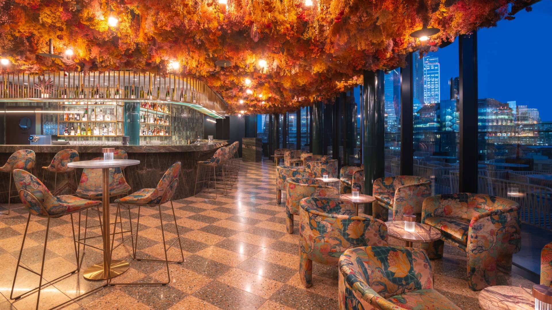 11 Rooftop Bars & Restaurants in the City of London - Florattica at Canopy by Hilton 11 Rooftop Bars & Restaurants in the City of London - Florattica at Canopy by Hilton - corner bar, with lounge and high seating, dense flowers hang from the ceiling