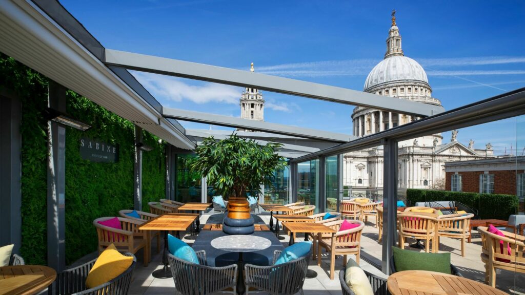 11 Rooftop Bars & Restaurants in the City of London - Sabine Outdoor rooftop bar(Sabine) - tables and chairs set out on the terrace with a stunning view of St Paul's Cathedral in the background.