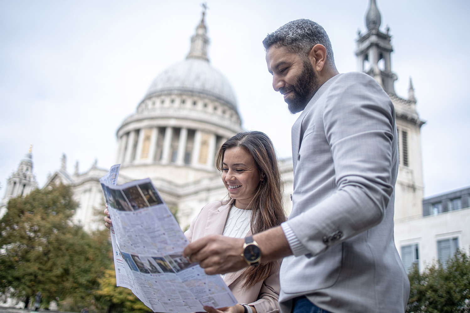 Two people look at a map. St Paul's Cathedral is visible in the background.