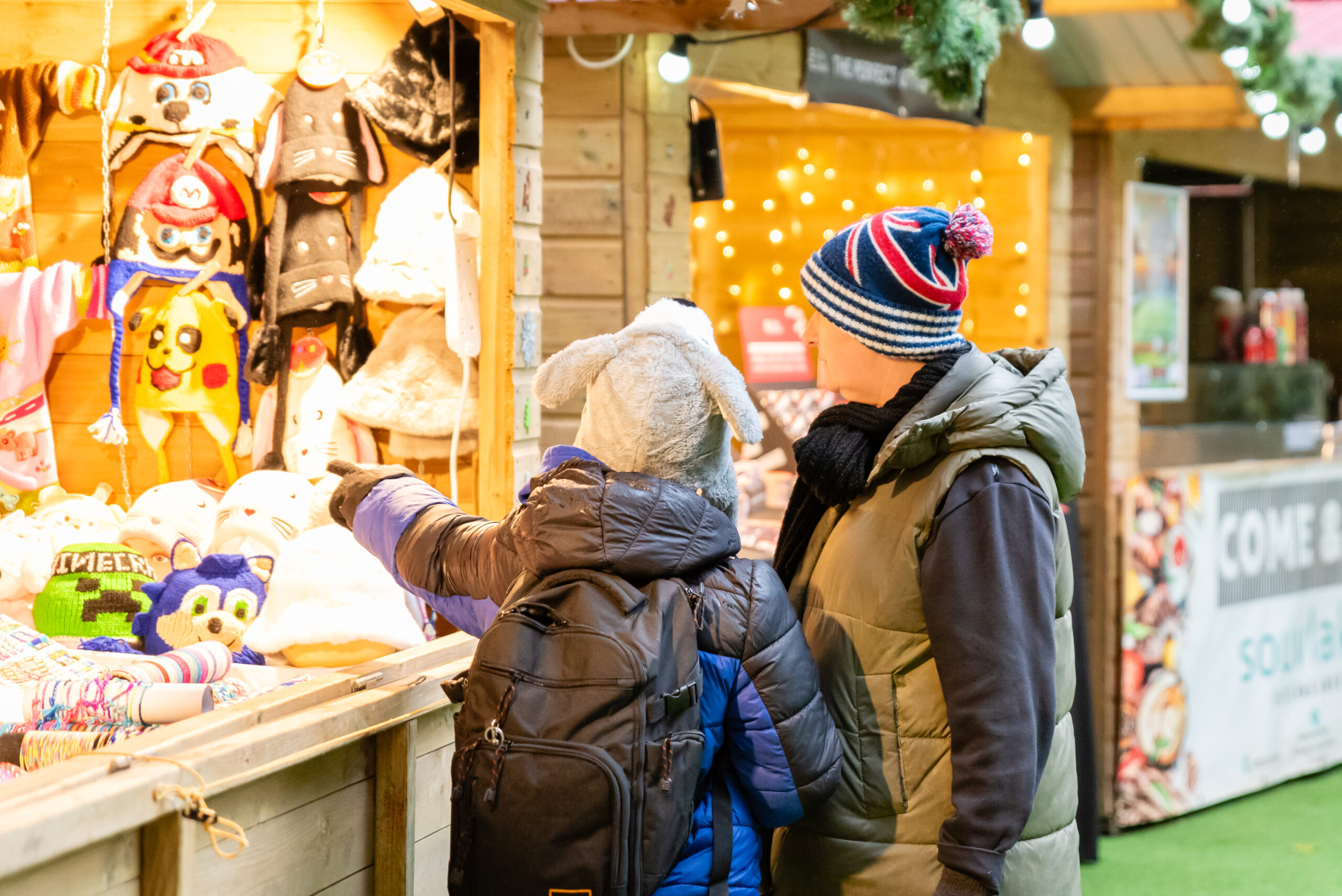 Two people at a Christmas market stall browsing gifts.