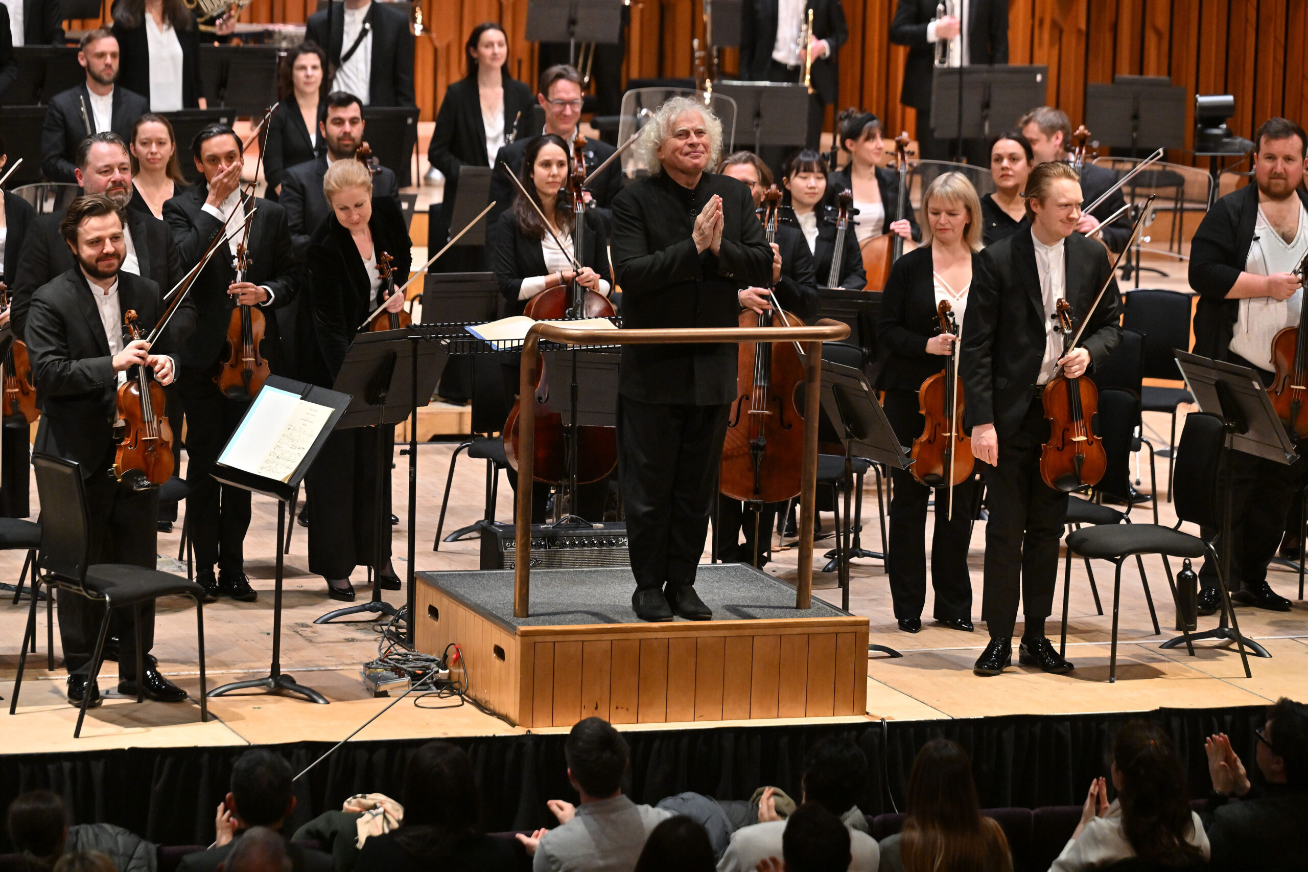 A group photo of a symphonic orchestra and its conductor.