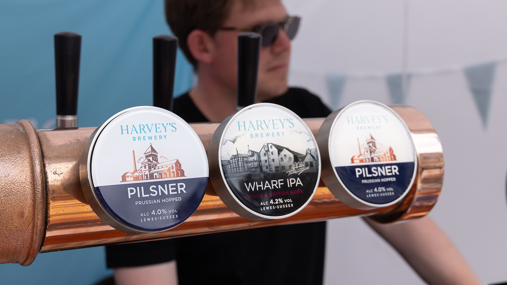 A close-up view of three beer taps, each adorned with different brand logos.