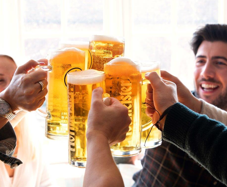 Close-up of a group of people clinking large glasses of beer.