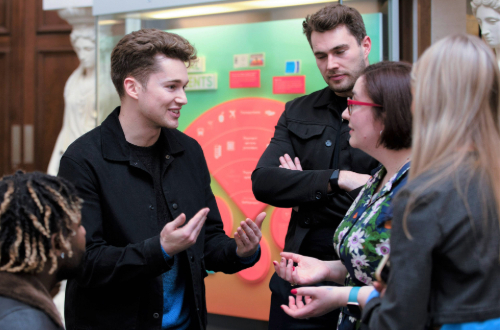 A person talking to a group of three people in an exhibition space.