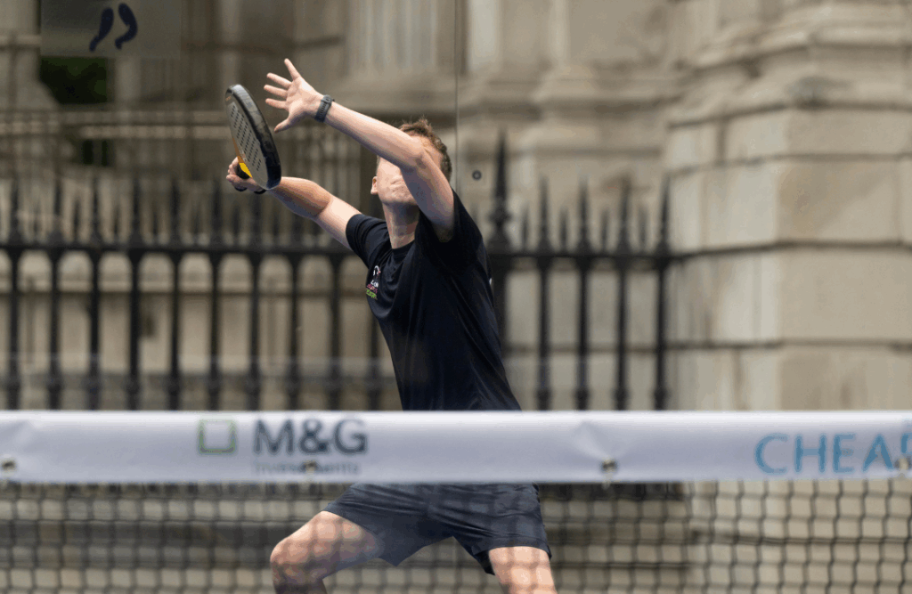 Person playing padel in front of a net with the logo of M&G Investments and Cheapside BID visible.