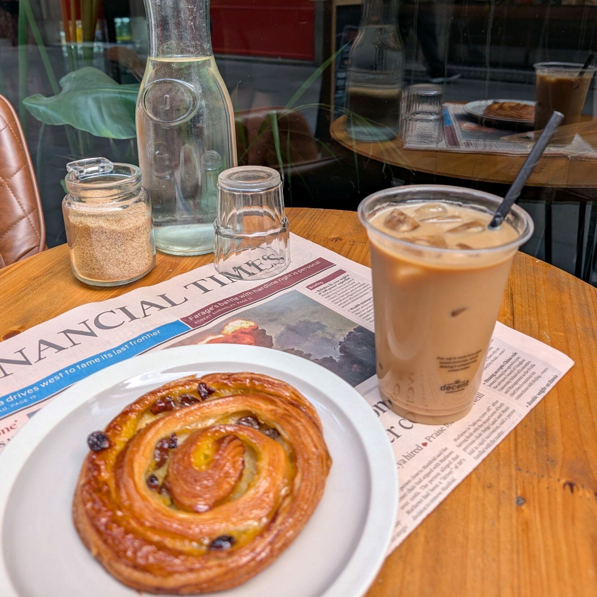 Close up shot of a pastry paired with an iced drink on top of a Financial Times newspaper