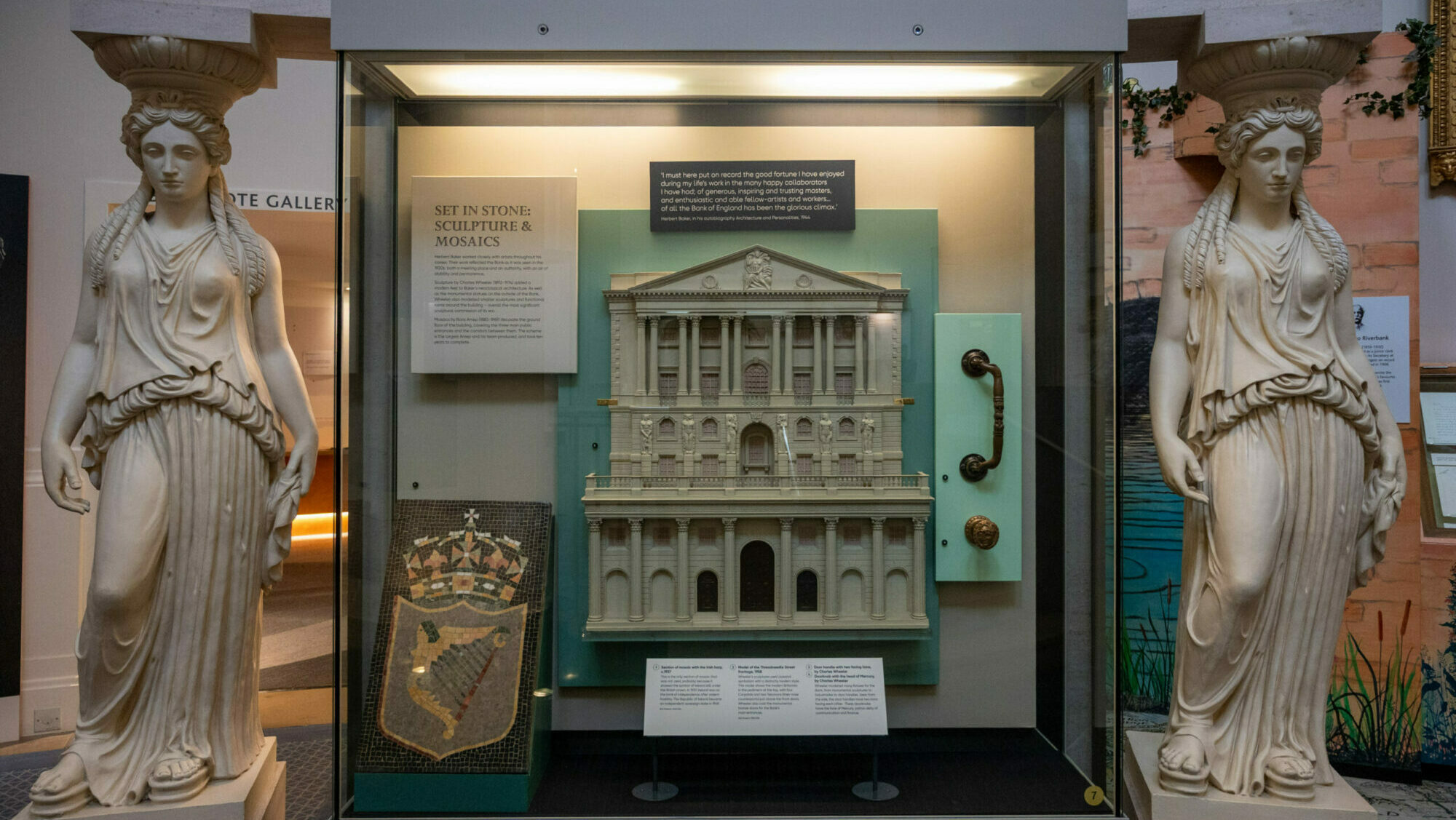 Image of a miniature Bank of England in a case surrounded by two old looking statues