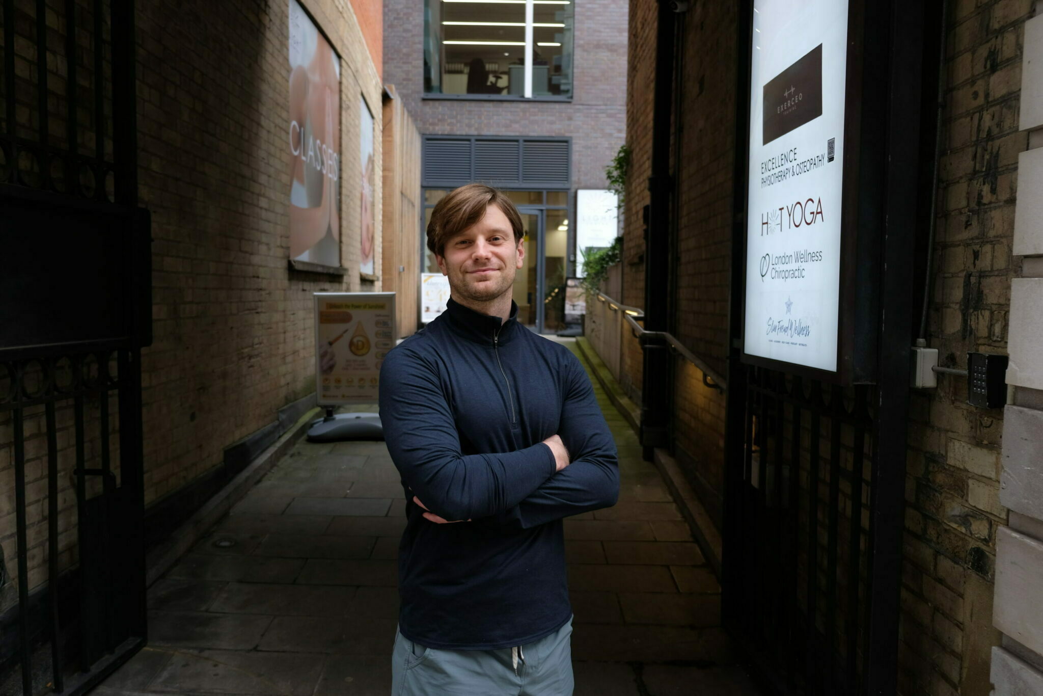 Image of a person standing cross armed in an alley looking into the camera