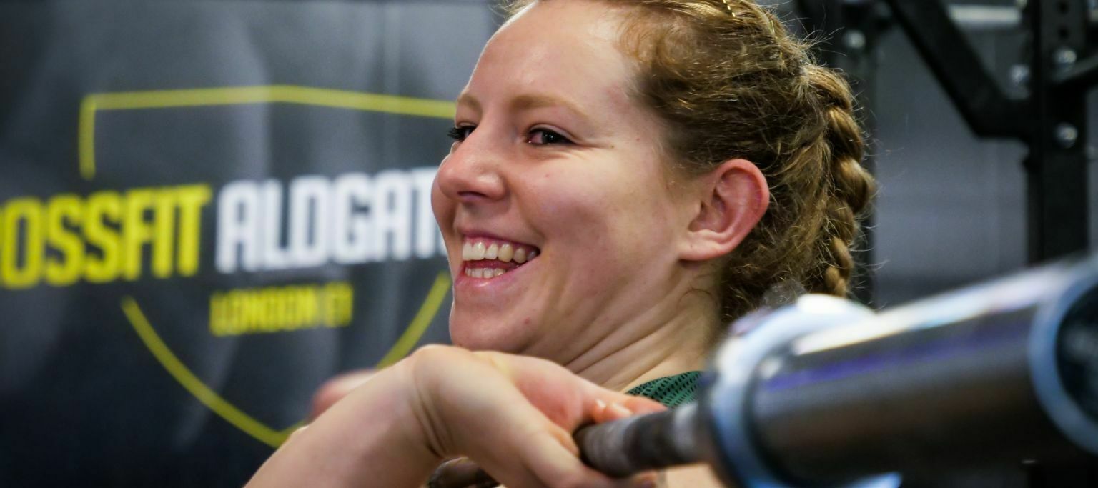 Close up of someone holding an weight bar with the Crossfit Aldgate logo in the background