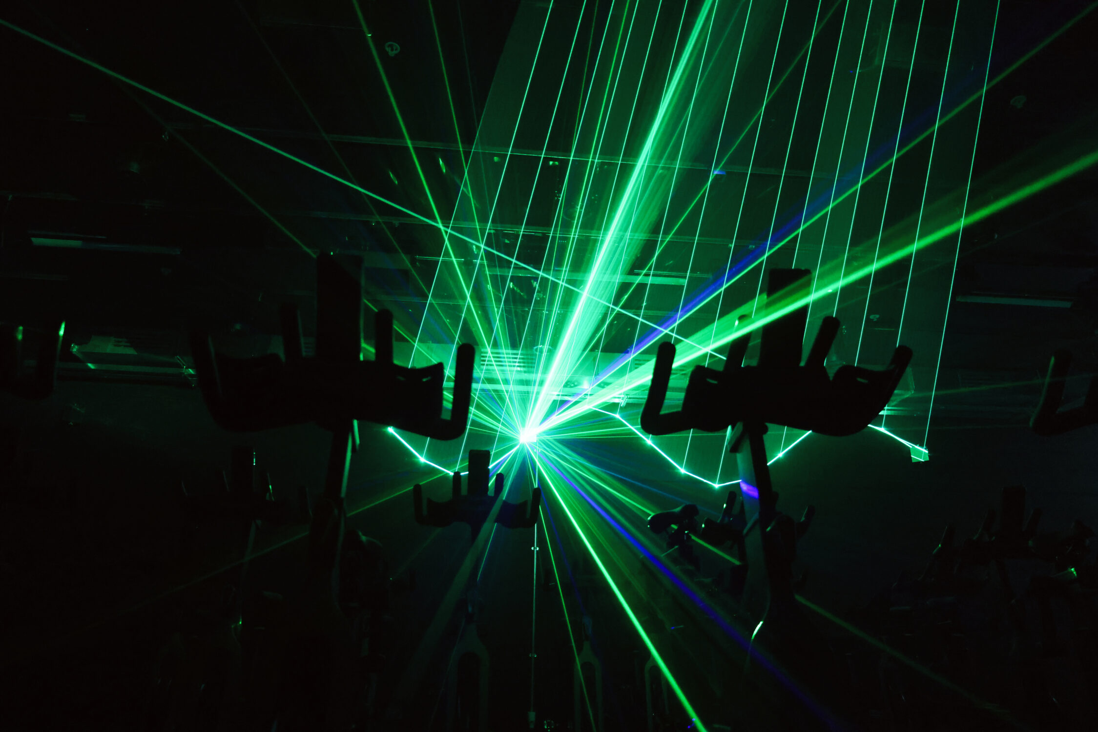 Lazers shooting from behind exercise bikes while the room is dark