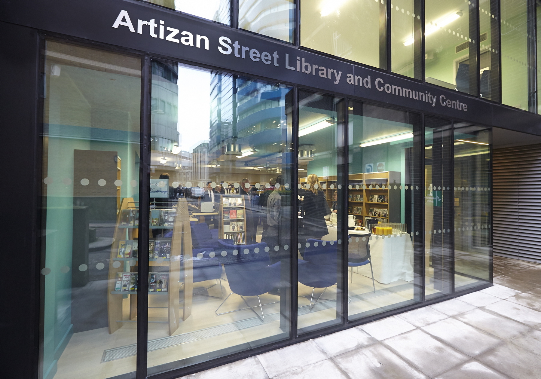 The entrance to the Artizan Street Library showing a glass door with the place name above the door in large letters.