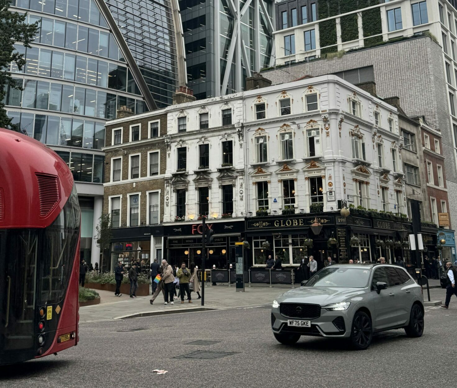 An image of the Globe pub from across the road, a red bus is in frame and a large glass building is behind it.