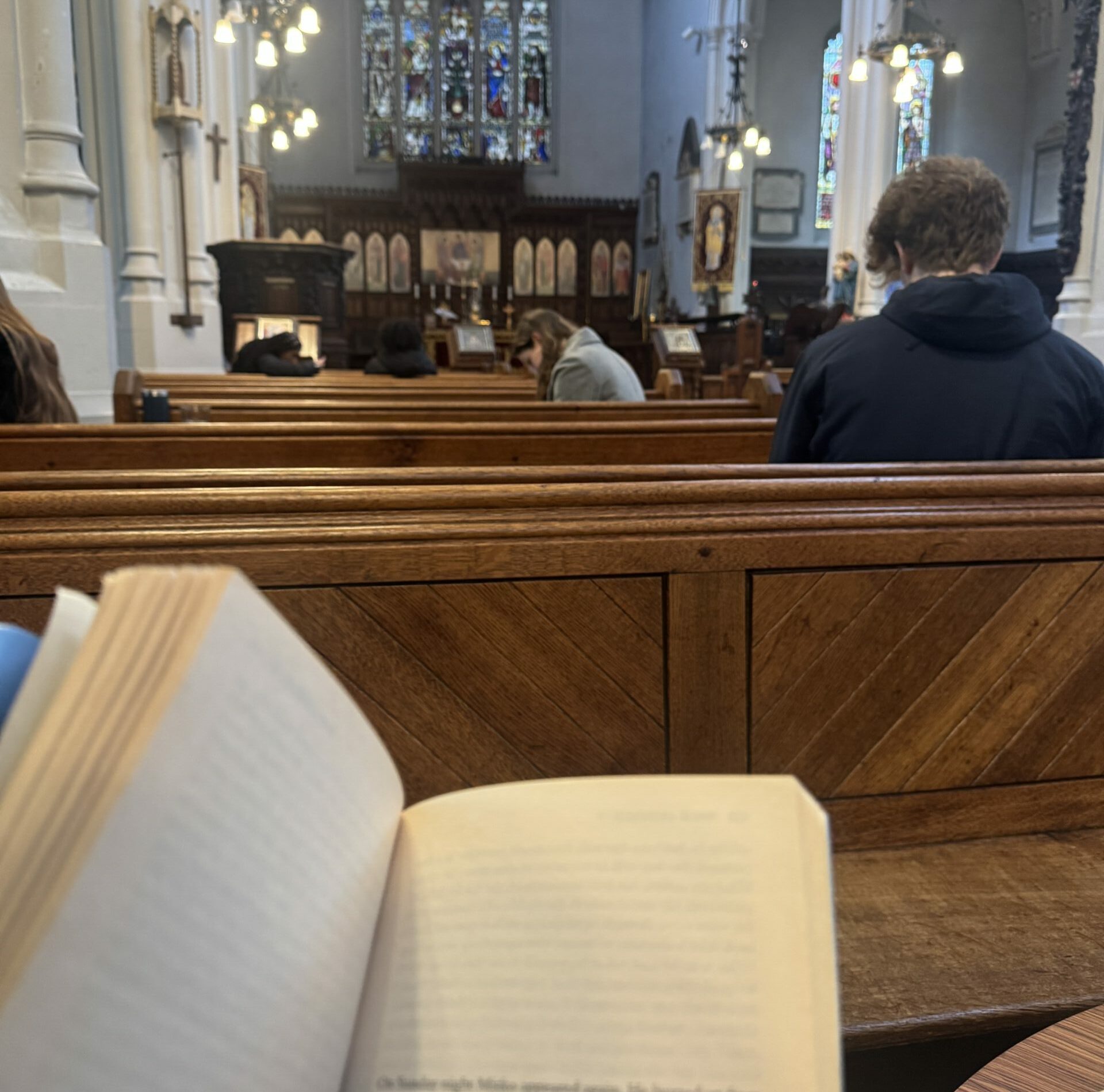An open book with a church pew and an altar in the background