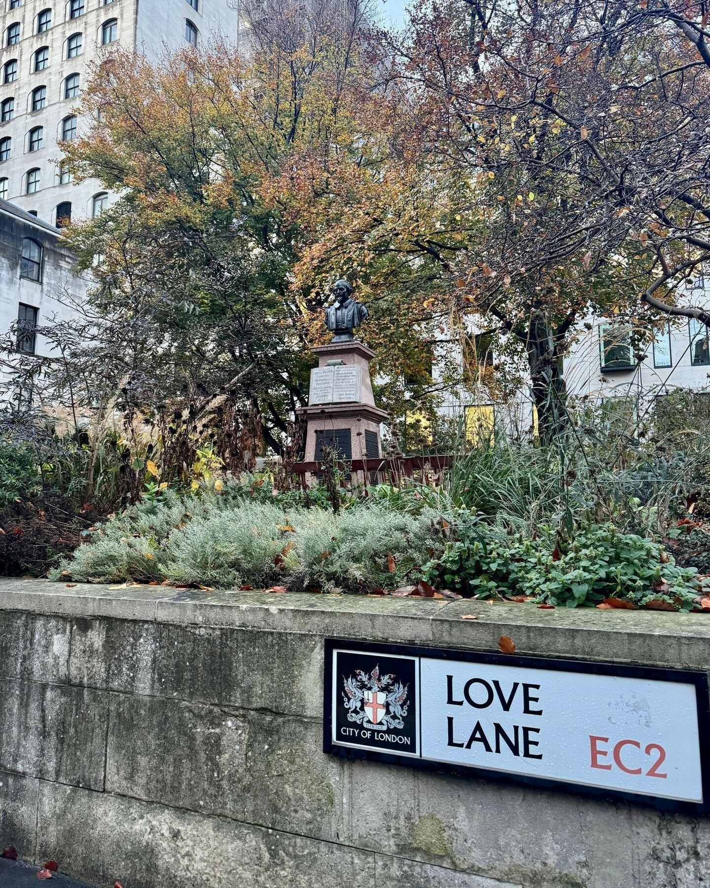 The Love Lane sign infront of the Shakespeare statue with greenery in the background